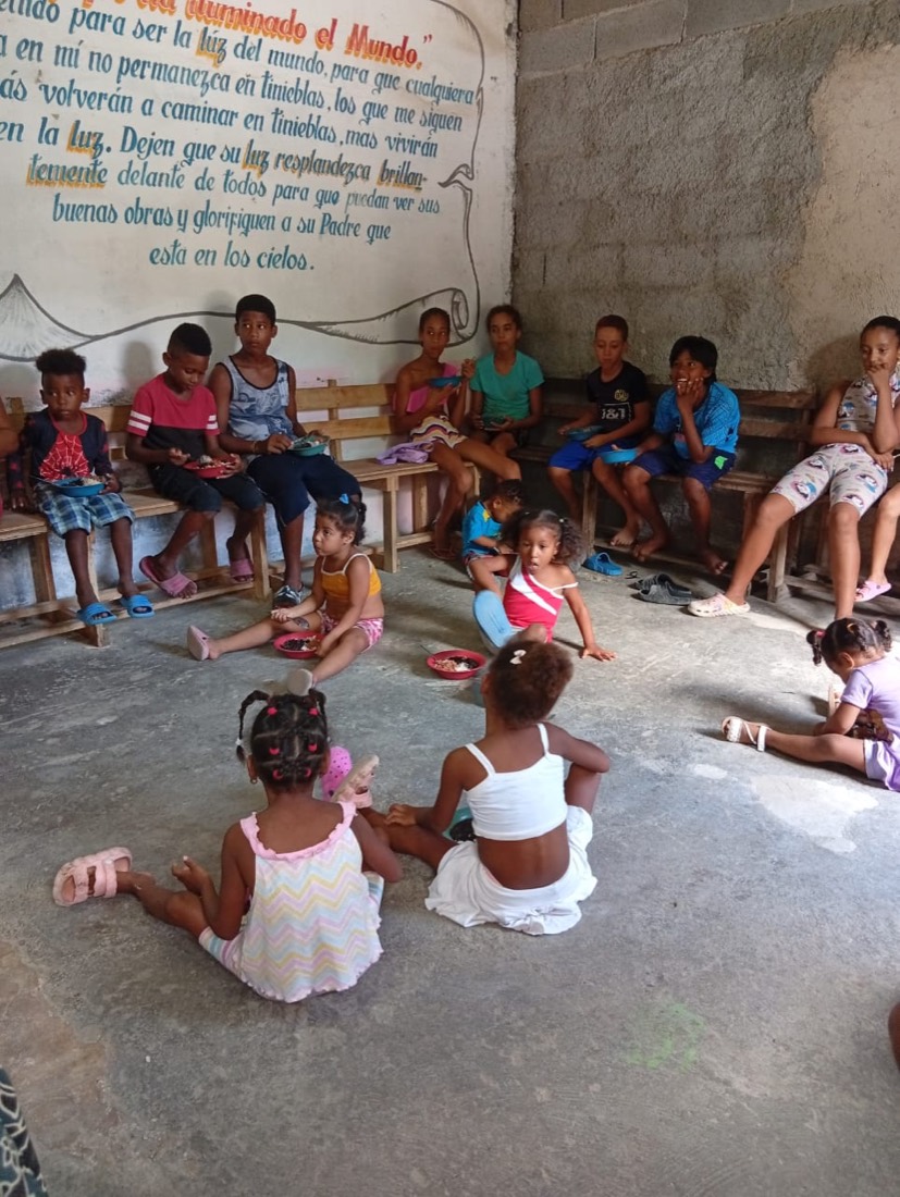 Niños reunidos comiendo en la obra misionera
